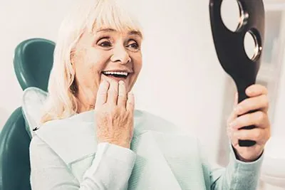 patient happy with her new all-on-4 dental implants smiling in the mirror