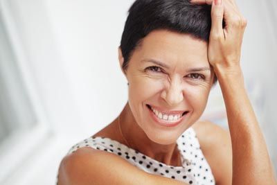 woman showing off her restored smile after getting dentures